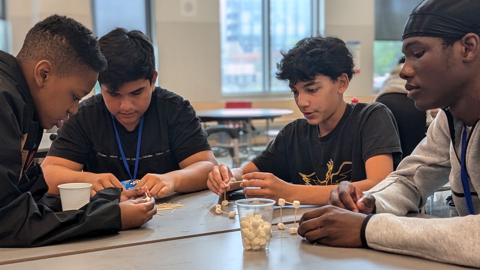 Four campers work together on a hands-on marshmallow and toothpick challenge.