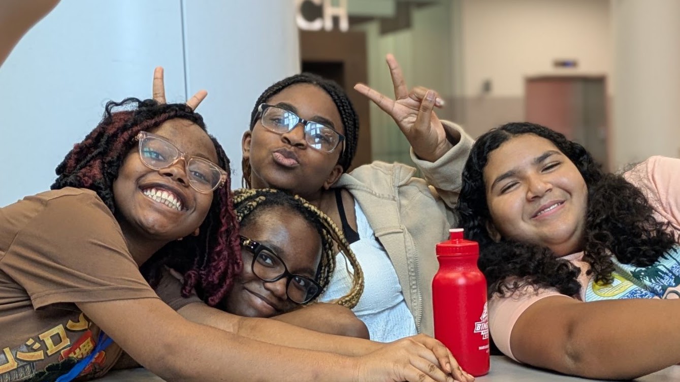 Four campers smile, hug, and pose together during Boston Debate League summer camp.